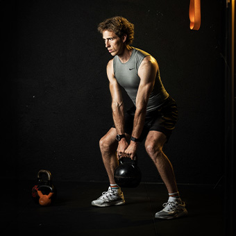 Mann trainiert mit einer Kettlebell, unterstützt durch eine proteingerechte Ernährung zur Deckung seines Proteinbedarfs.