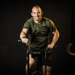 Mann trainiert auf einem Fahrrad-Ergometer, um seinen Proteinbedarf nach dem Training zu optimieren.