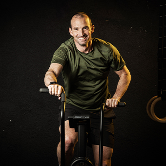 Mann trainiert auf einem Fahrrad-Ergometer, um seinen Proteinbedarf nach dem Training zu optimieren.