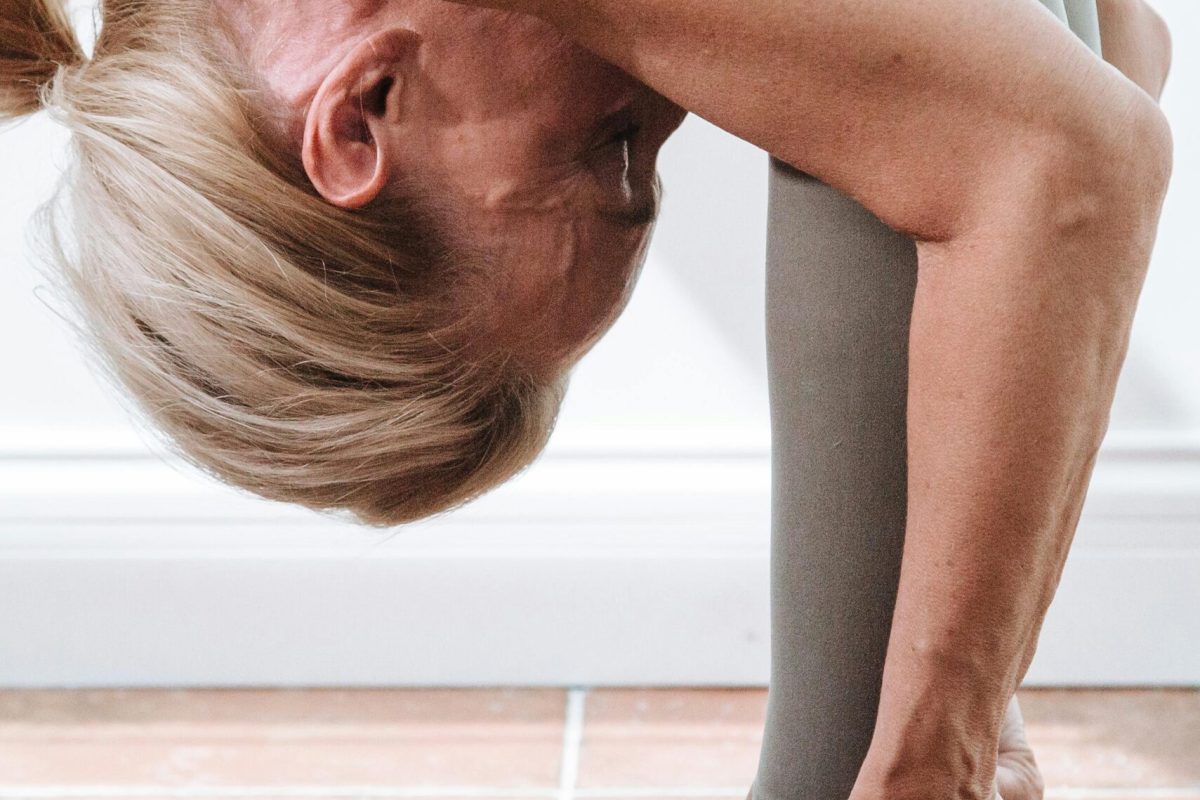 Frau bei einer Vorwärtsbeuge-Dehnübung, um den Alterungsprozess ab 40 zu kontrollieren und Flexibilität sowie Beweglichkeit zu fördern.